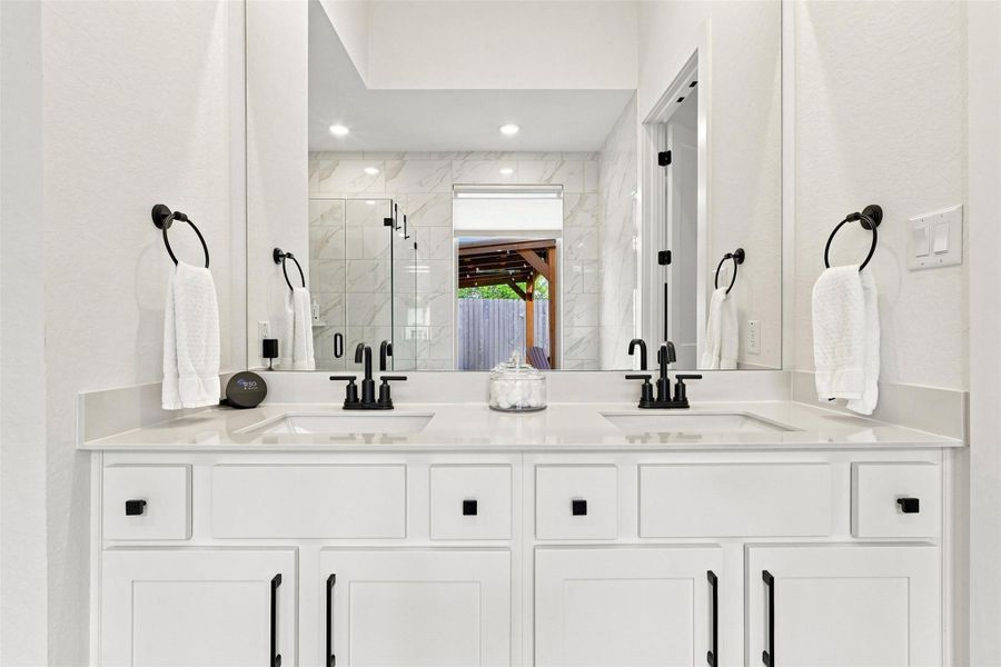 A spacious double vanity anchors this modern bathroom with clean white cabinetry and stone counters.