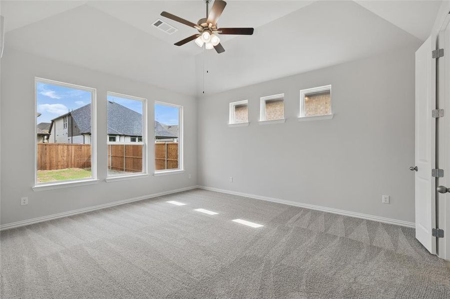 Empty room with a ceiling fan, light colored carpet, and vaulted ceiling