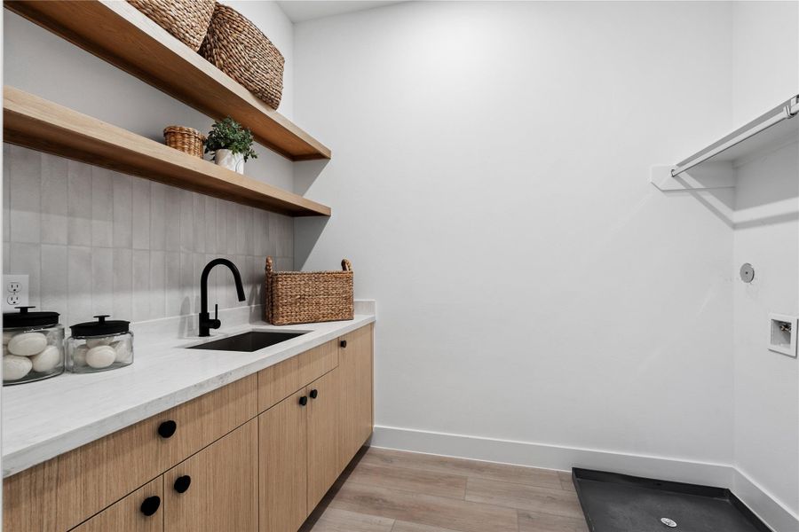 Thoughtfully appointed with abundant cabinetry and a modern sink, this laundry space blends function with elevated design.