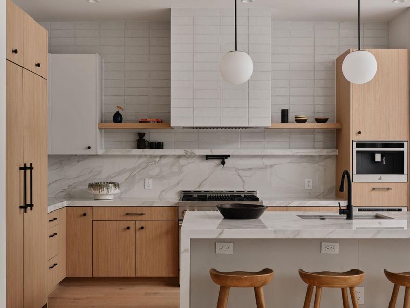 Contemporary kitchen featuring light wood-finish cabinetry, white slab countertops with integrated sink, a matching backsplash, and a built-in coffee system