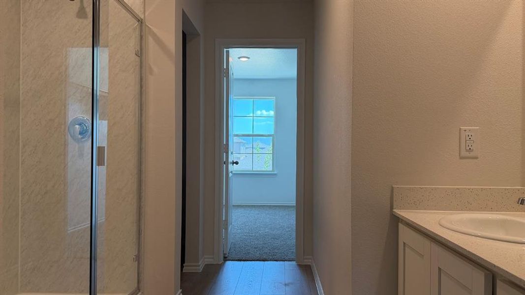 Bathroom featuring a glass-enclosed shower, single vanity with a solid surface countertop, wood-finish flooring, and neutral wall tones