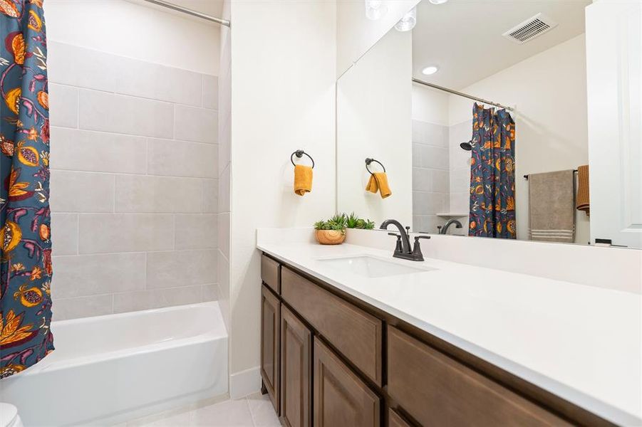 Full bathroom featuring vanity, shower / bathtub combination with curtain, and light tile patterned floors