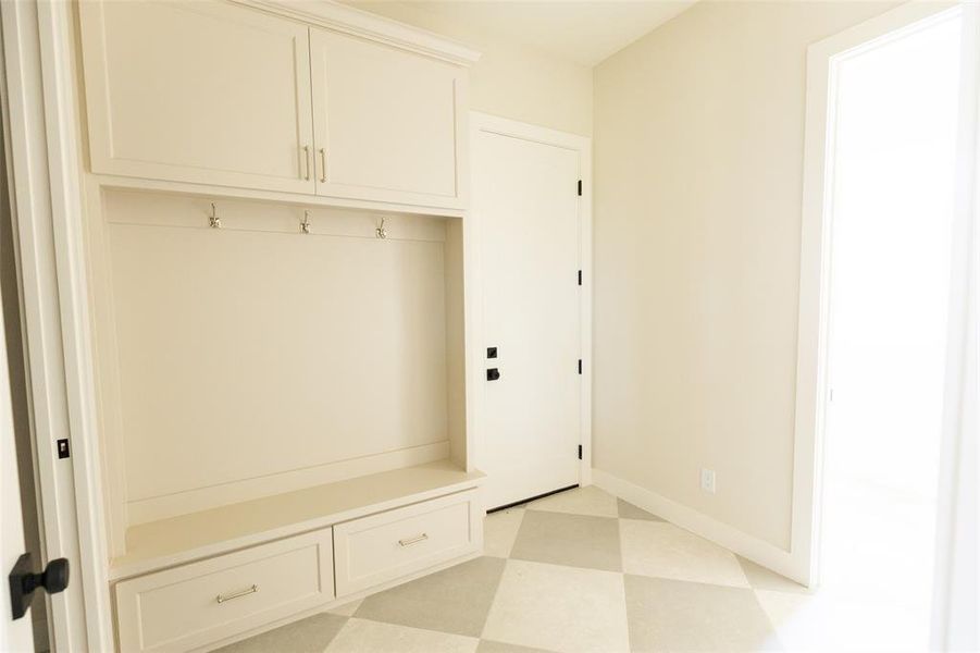 Built-in storage unit featuring upper cabinetry, coat hooks, and lower drawers, complemented by a bench