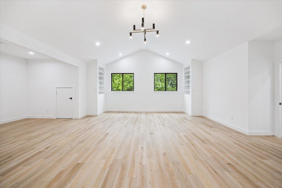 Spacious upstairs game room with vaulted ceilings, built-in shelving, and modern lighting provides the perfect blank canvas for play, relaxation, or media. Twin windows frame views of the treetops, bringing in natural light and a sense of calm. Spacious upstairs game room with vaulted ceilings, built-in shelving, and modern lighting provides the perfect blank canvas for play, relaxation, or media. Twin windows frame views of the treetops, bringing in natural light and a sense of calm.