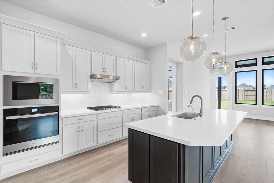 The chef’s kitchen, where a striking contrast island takes center stage. The island beautifully offsets the crisp perimeter cabinetry, creating a high-end, two-tone aesthetic. This intentional design choice adds depth and character to the open-concept space and an expansive countertop that invites both meal prep and casual entertaining.