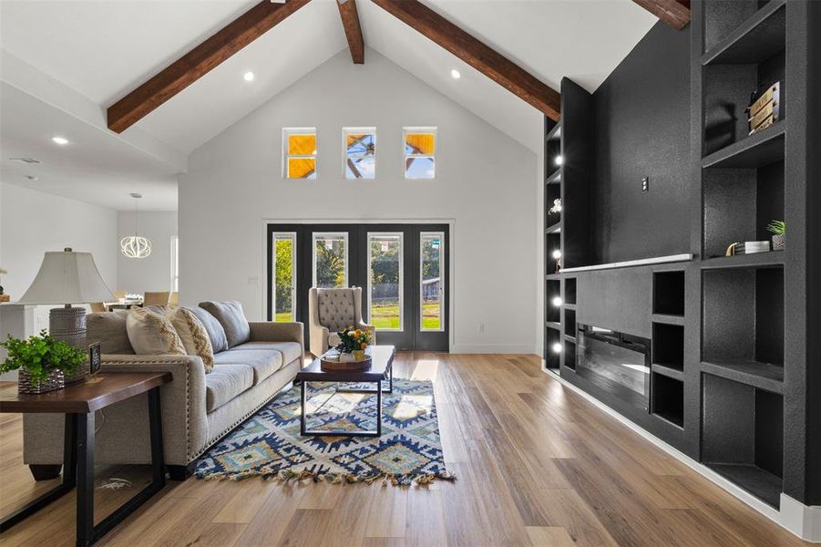 Living room with beam ceiling, high vaulted ceiling, light wood-style flooring, recessed lighting, and built in shelves