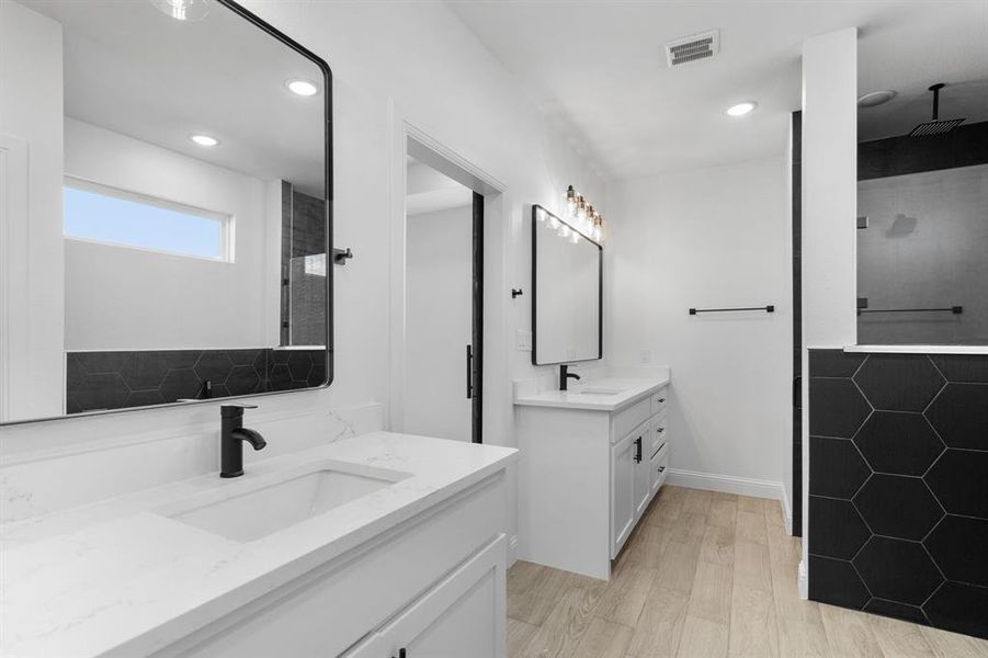 Bathroom featuring hardwood / wood-style flooring, vanity, and tiled shower