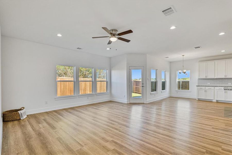 living room with ceiling fan with notable chandelier and light wood-type flooring living room with ceiling fan with notable chandelier and light wood-type flooring