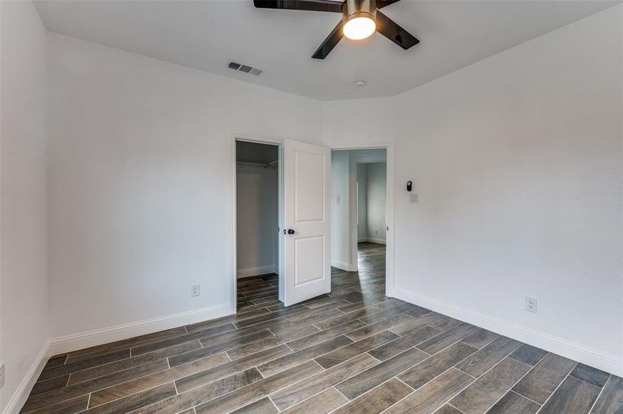 Unfurnished bedroom with wood finish floors, a spacious closet, and ceiling fan Unfurnished bedroom with wood finish floors, a spacious closet, and ceiling fan