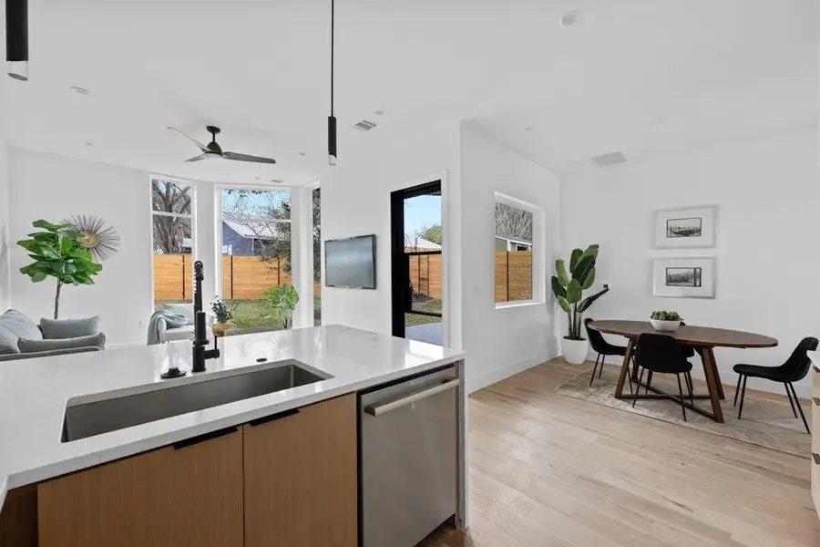 Kitchen featuring light stone counters, dishwasher, open floor plan, light wood-type flooring, and a ceiling fan