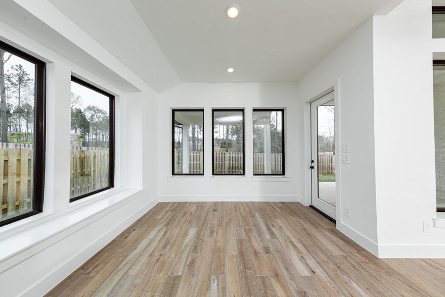 The dining area is filled with natural light and features high ceilings, recessed lighting, expansive windows, and a window seat that expands the length of the two large windows.