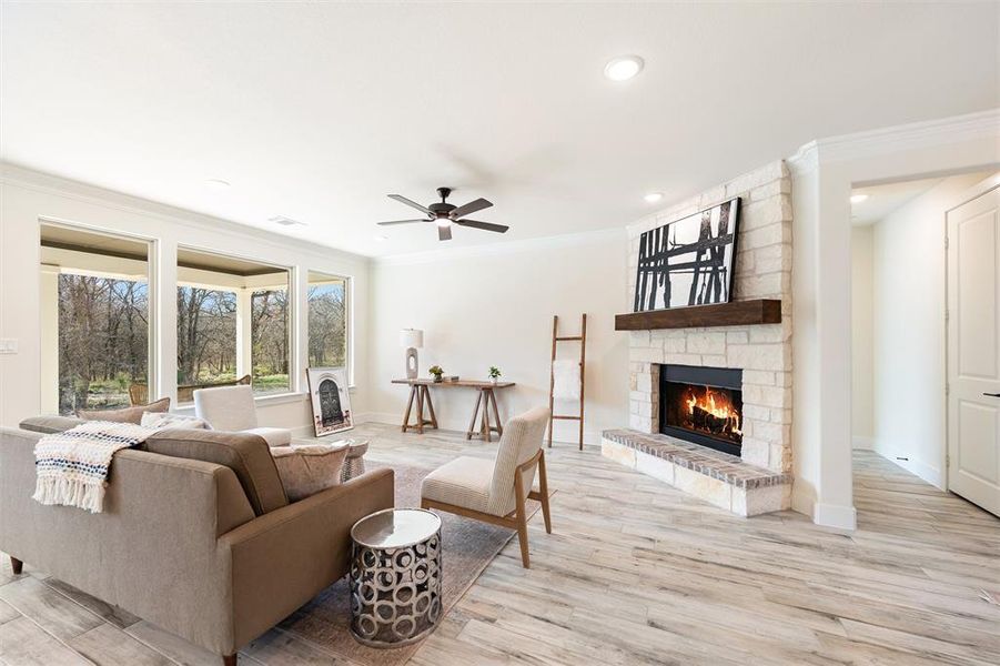 Living area with a fireplace, a ceiling fan, light wood-type flooring, crown molding, and recessed lighting