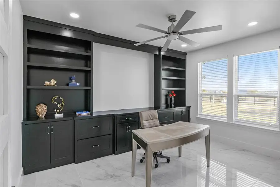 Office area featuring built in shelves, ceiling fan, recessed lighting, and light marble finish floors Office area featuring built in shelves, ceiling fan, recessed lighting, and light marble finish floors