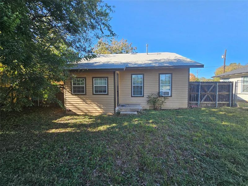 Rear view of property with cooling unit and a lawn Rear view of property with cooling unit and a lawn