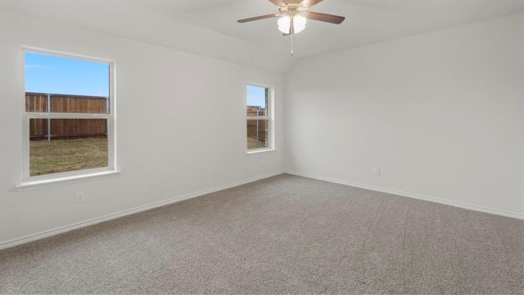 Spacious room featuring neutral carpet, vaulted ceiling, and a ceiling fan with integrated lighting