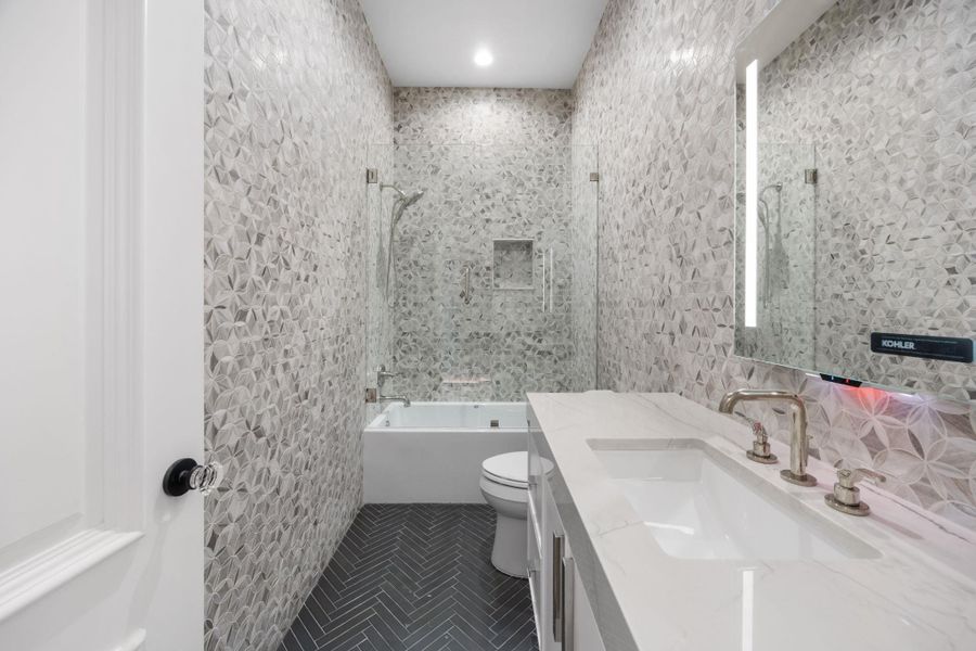 Herringbone floor tiles complement a textured accent wall in this sleek bathroom. Herringbone floor tiles complement a textured accent wall in this sleek bathroom.