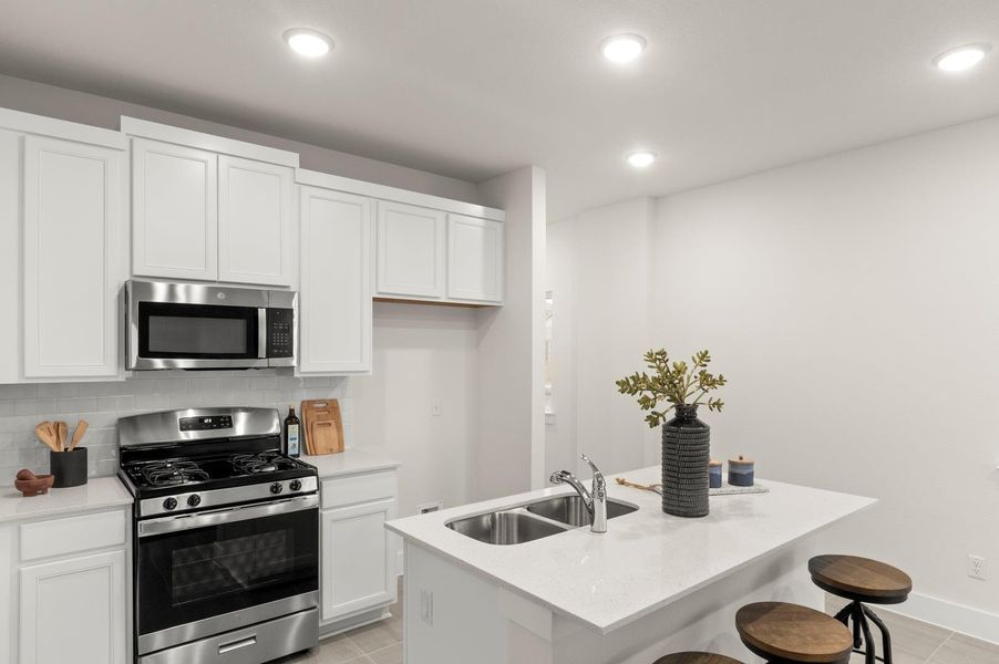 A well-lit kitchen with sleek white cabinetry and a practical island workspace.