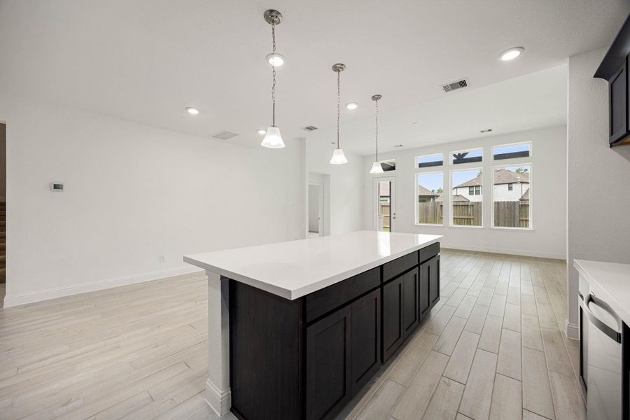 Spacious kitchen with a large island, modern pendant lighting, and abundant natural light from expansive windows, perfect for entertaining.