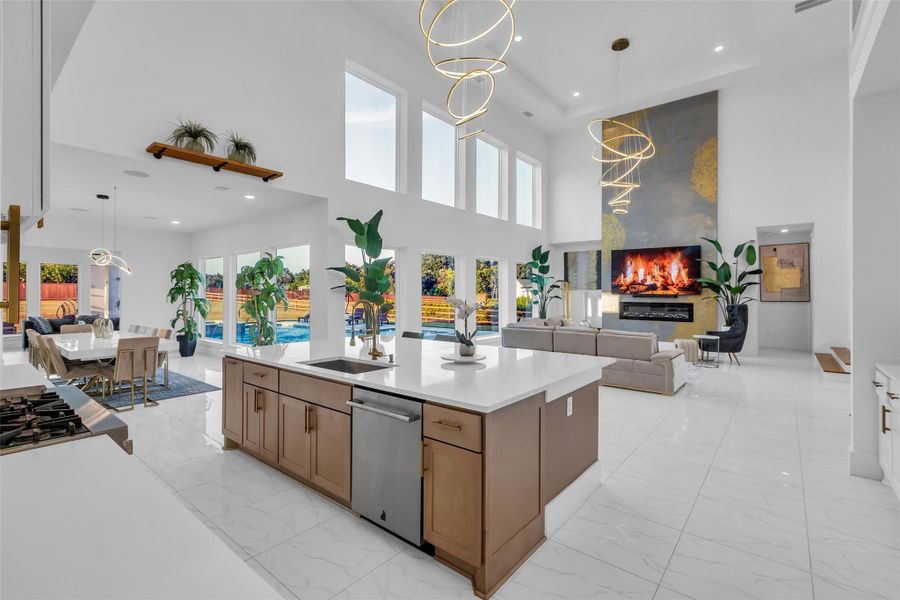 Kitchen, Dining & Great Room: Open-concept living with soaring ceilings, designer lighting, and walls of windows overlooking the pool, seamlessly blending dining, entertaining, and a chef’s island kitchen with sleek modern finishes.