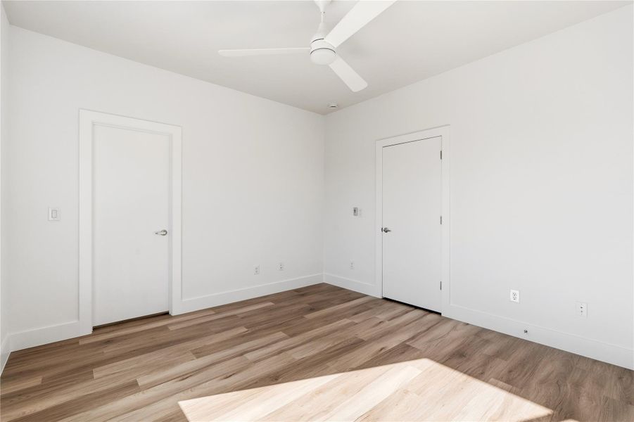 Guest bedroom with a ceiling fan, walk-in closet, and LVP flooring.