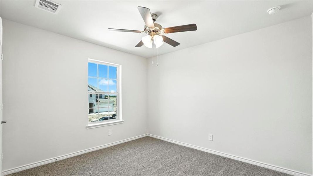 Unfurnished room featuring dark colored carpet and a ceiling fan