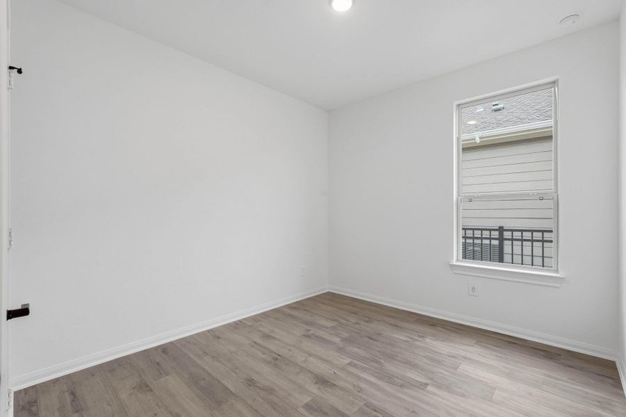 This cozy, sunlit room is perfect for a home office or reading nook, with multiple windows and a glass door that flood the space with natural light.