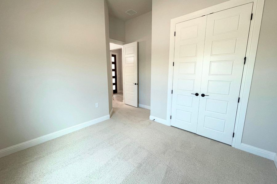 Soft carpeting pairs with crisp baseboards and paneled double doors in this versatile room. Soft carpeting pairs with crisp baseboards and paneled double doors in this versatile room.