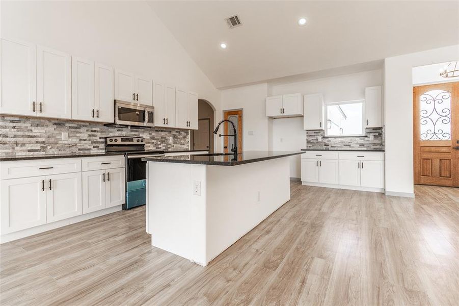 Kitchen with light hardwood / wood-style flooring, stainless steel appliances, sink, a center island with sink, and white cabinets