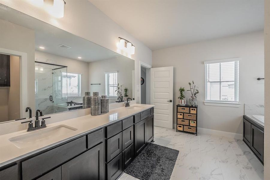 Full bath with double vanity, a marble finish shower, light marble finish flooring, and a tub to relax in
