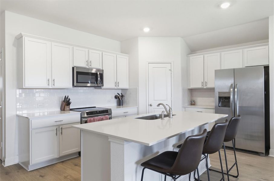 Kitchen featuring light-toned wood-finish flooring, white cabinetry with brushed nickel hardware, and a white subway tile backsplash