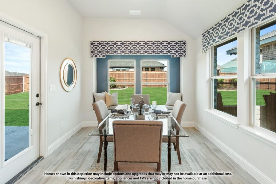Bright dining area with glass table, vaulted ceiling, large windows, and backyard views