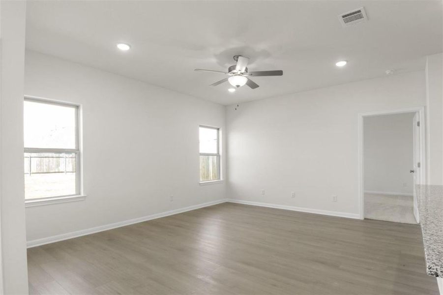 Spare room with a ceiling fan, visible vents, baseboards, and wood finished floors