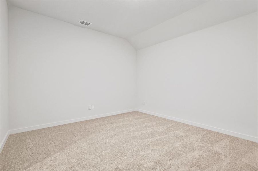 Carpeted empty room featuring lofted ceiling