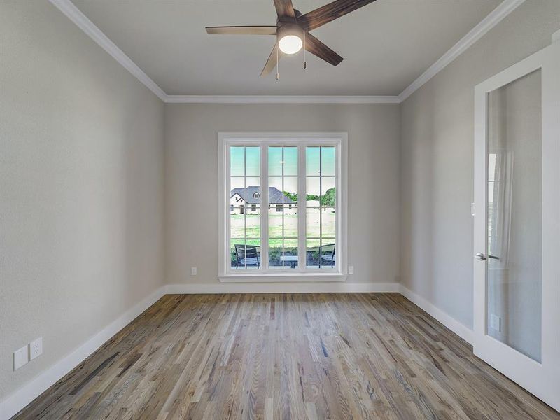 Empty room featuring wood finished floors, ornamental molding, and ceiling fan Empty room featuring wood finished floors, ornamental molding, and ceiling fan