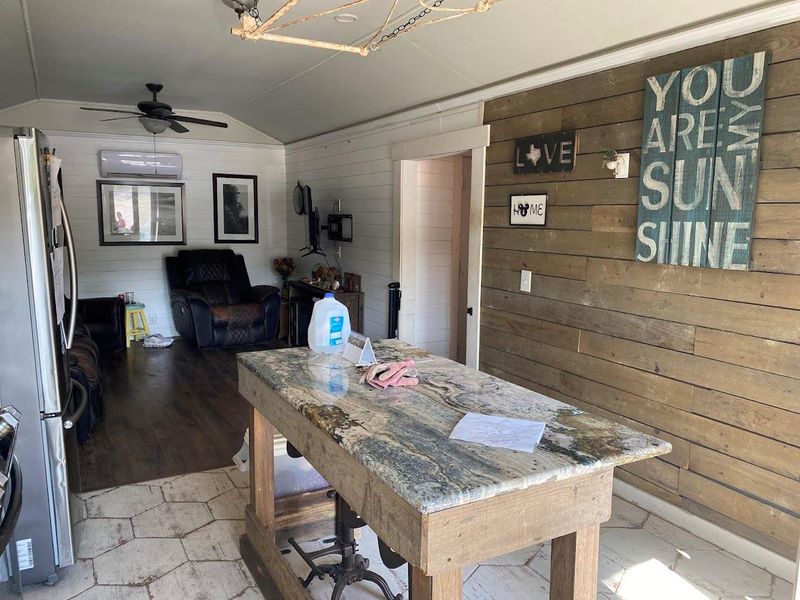 Dining area featuring vaulted ceiling, wood walls, ceiling fan, and a wall mounted AC