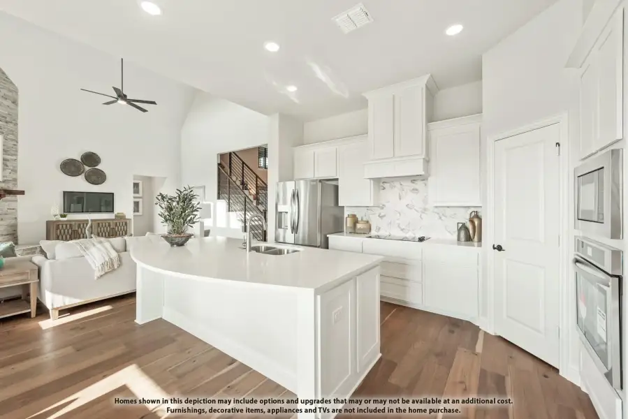 Open kitchen with white cabinets, curved island, marble backsplash, and stainless appliances, open to living room with hardwood floors Open kitchen with white cabinets, curved island, marble backsplash, and stainless appliances, open to living room with hardwood floors