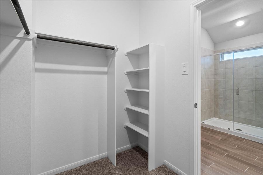 The primary suite features a generous walk-in closet equipped with functional hanging rods and shelving.