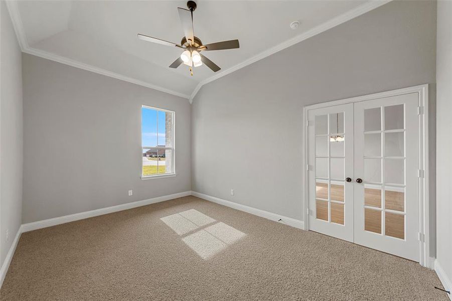 Carpeted spare room with ceiling fan, french doors, lofted ceiling, and ornamental molding