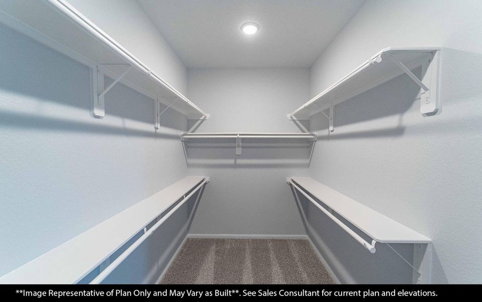 Primary bedroom walk-in closet offering generous space for clothing, shoes, and personal belongings. Designed with comfort and convenience in mind, featuring soft carpet flooring and bright recessed lighting to keep everything easy to see and access. **Image Representative of Plan Only and May Vary as Built**.