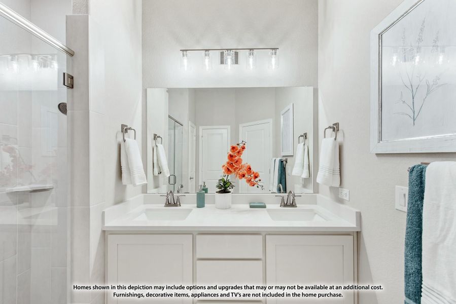 Bathroom with double-sink vanity, white cabinets, large mirror, and glass shower enclosure