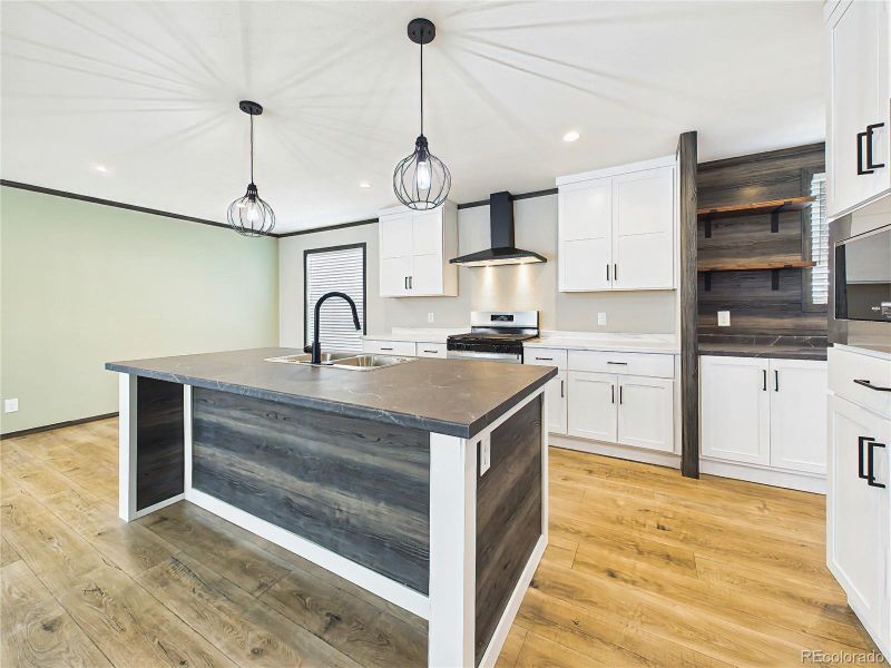 Kitchen – Stylish open-concept kitchen featuring a large island with seating, pendant lighting, stainless steel appliances, and modern cabinetry.
