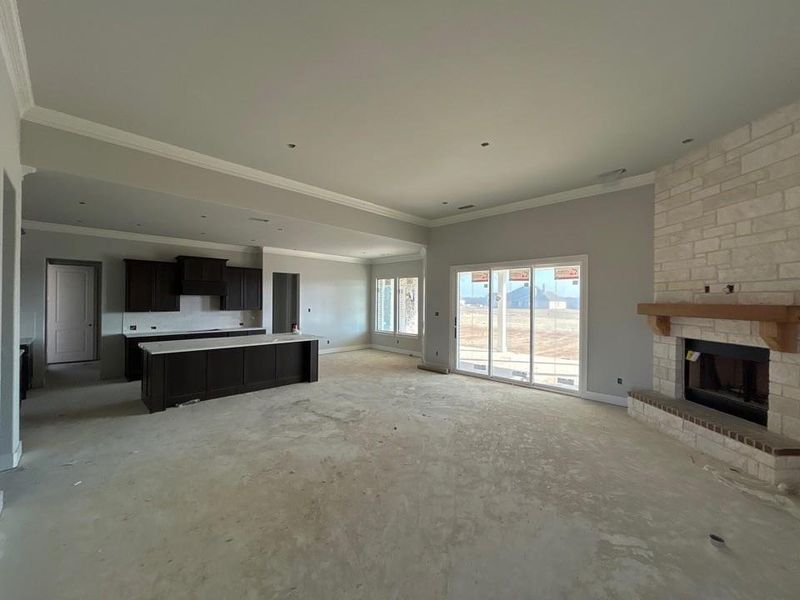 Unfurnished living room featuring a large fireplace and ornamental molding