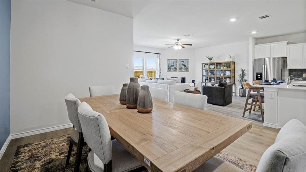 Open-concept dining and living area featuring wood-finish flooring, recessed lighting, and a ceiling fan Open-concept dining and living area featuring wood-finish flooring, recessed lighting, and a ceiling fan