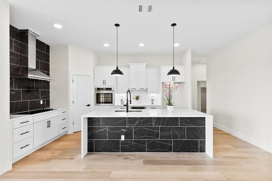 Kitchen featuring oven, decorative backsplash, black electric stovetop, light countertops, and a sink Kitchen featuring oven, decorative backsplash, black electric stovetop, light countertops, and a sink