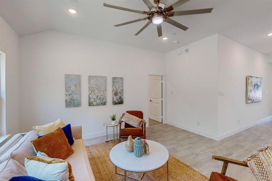 Living room featuring light wood-type flooring, vaulted ceiling, and ceiling fan