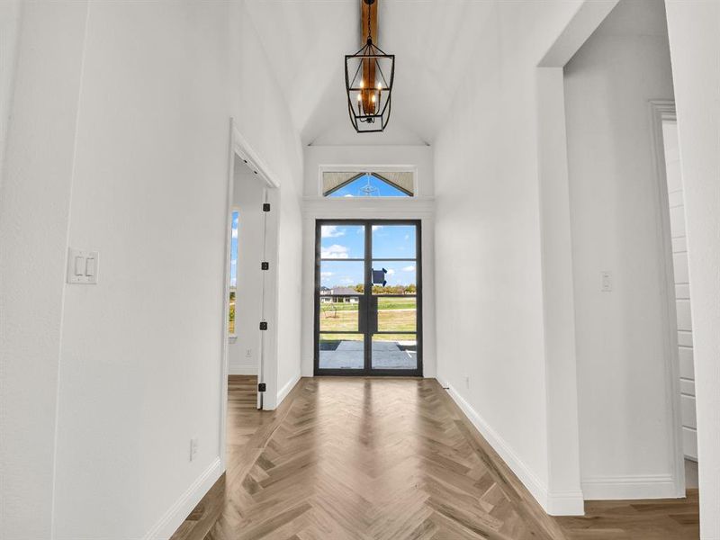 Foyer entrance featuring a chandelier, baseboards, and a towering ceiling Foyer entrance featuring a chandelier, baseboards, and a towering ceiling
