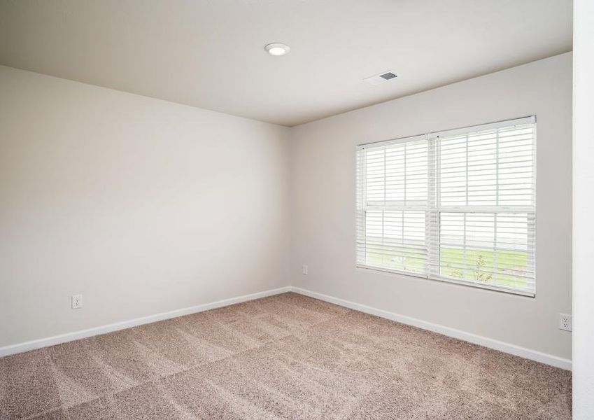 Secondary bedroom with tan walls and carpet and two large windows.