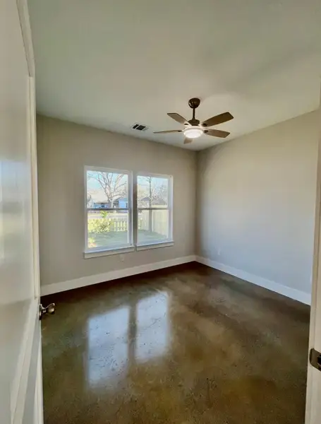 Unfurnished room featuring finished concrete flooring and a ceiling fan