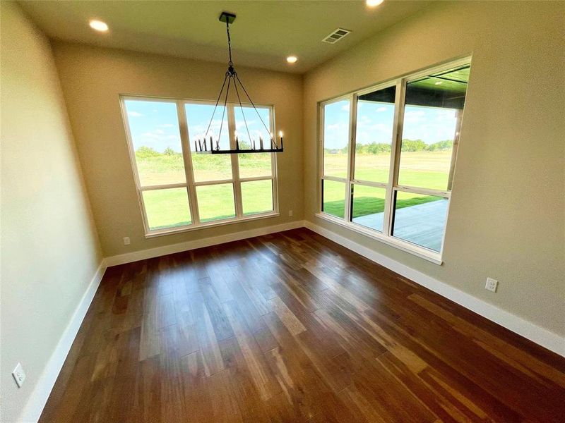 Unfurnished dining area featuring a notable chandelier and dark hardwood / wood-style floors