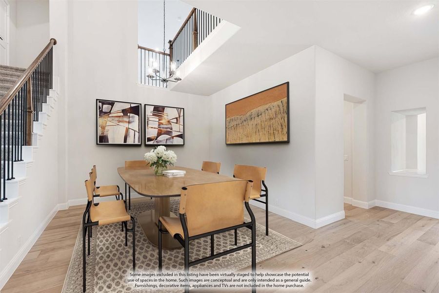 Dining room with two-story ceiling, wood table, tan leather chairs, and light hardwood floors next to staircase Dining room with two-story ceiling, wood table, tan leather chairs, and light hardwood floors next to staircase